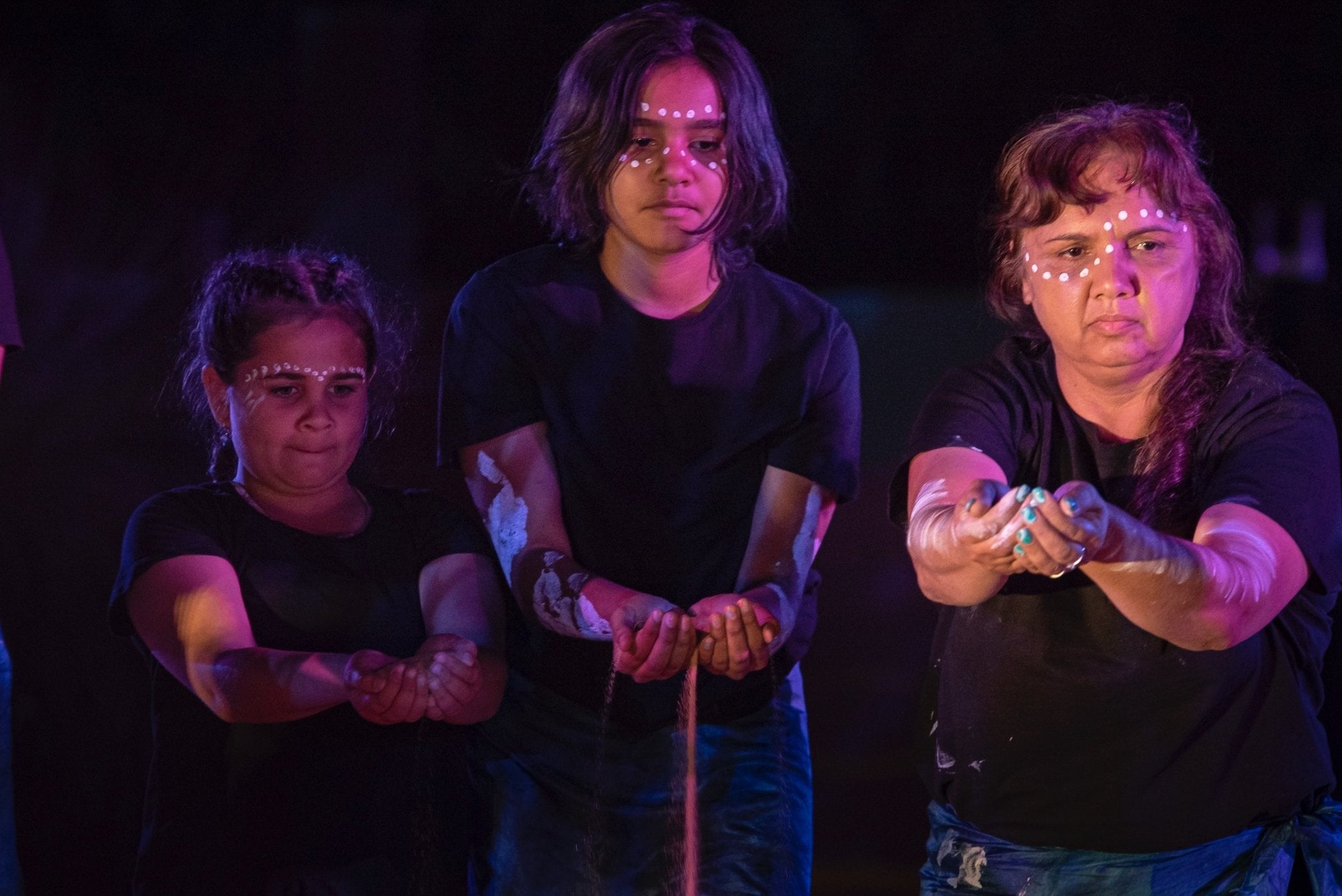 Three generations of indigenous woman performing a dance